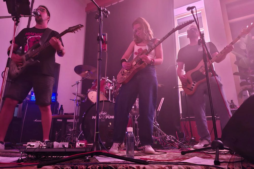 Fabi and The Papa Punks live auf der Bühne – drei Musiker mit Gitarren und Bass im pinken Bühnenlicht